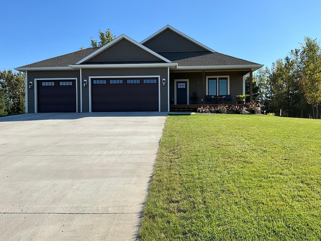 view of front of property featuring a front lawn, a porch, and a garage