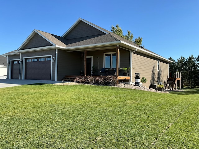 view of front of house featuring covered porch, a front yard, and a garage