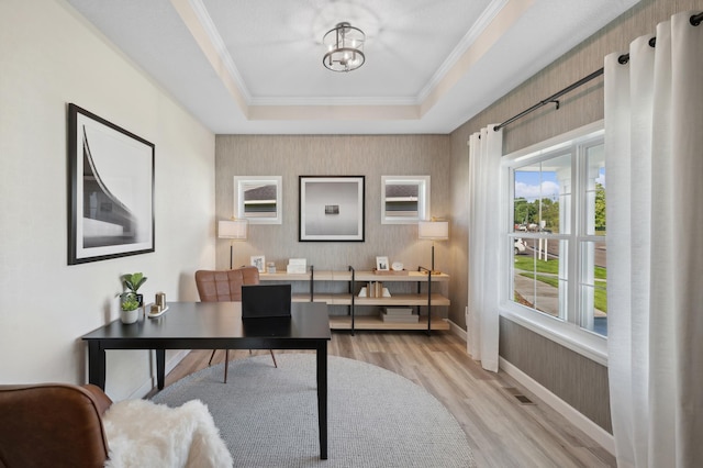 office space featuring ornamental molding, light hardwood / wood-style floors, a tray ceiling, and an inviting chandelier