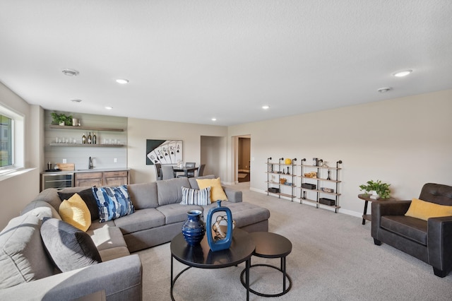 living room with wine cooler, a textured ceiling, light colored carpet, and wet bar