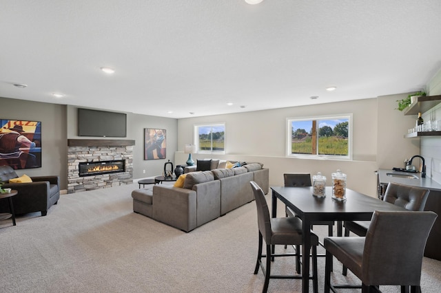 dining area featuring a stone fireplace, sink, and light colored carpet