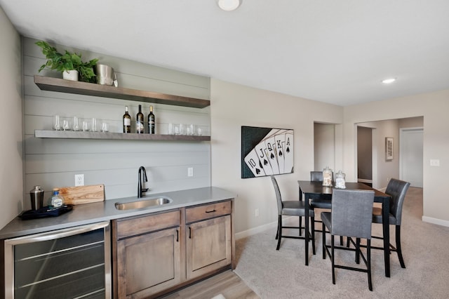 bar featuring beverage cooler, light hardwood / wood-style floors, and sink