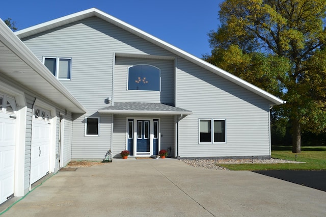 rear view of property featuring driveway and a shingled roof