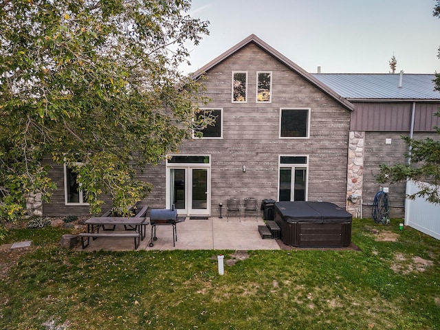 back of house with a yard, a patio area, and a hot tub