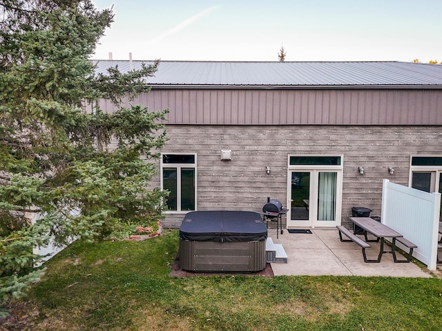 back of house with a lawn, a patio, and a hot tub