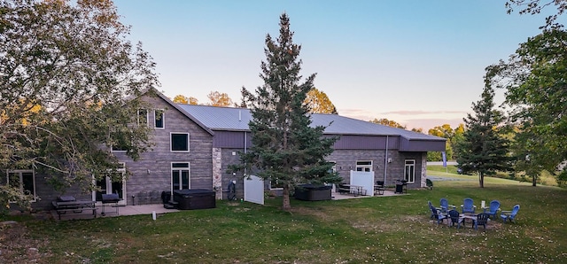 back house at dusk with a lawn and a patio area