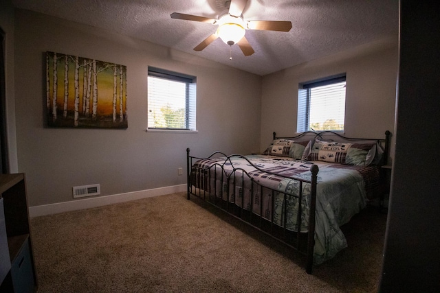 bedroom with ceiling fan, carpet floors, and a textured ceiling