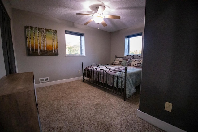 bedroom with a textured ceiling, carpet, and ceiling fan