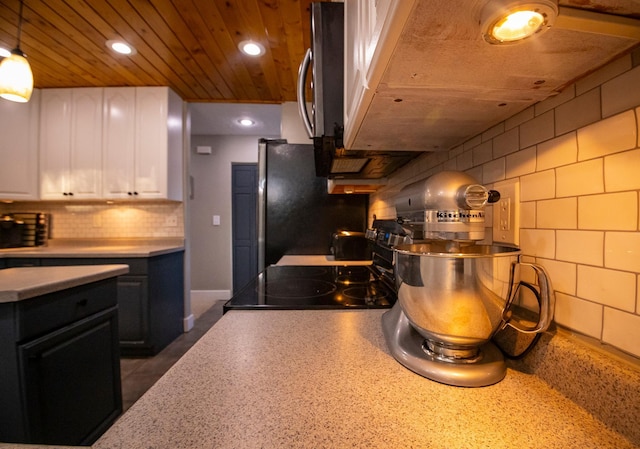 kitchen featuring decorative backsplash, white cabinets, exhaust hood, and hanging light fixtures