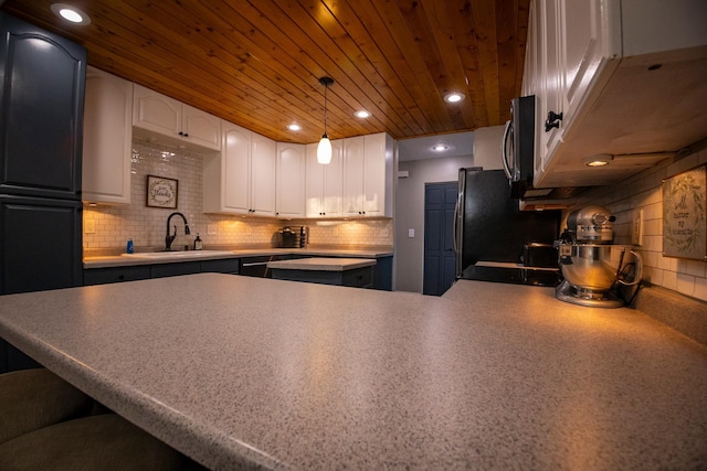 kitchen with backsplash, white cabinetry, sink, and pendant lighting