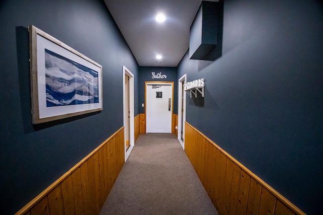 hall with wooden walls and light colored carpet