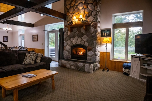 living room featuring a wealth of natural light, wooden walls, and a stone fireplace