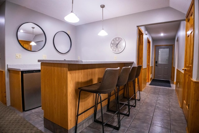 bar with dark tile patterned floors, wood walls, hanging light fixtures, and stainless steel dishwasher