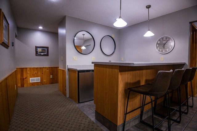 bar with pendant lighting, stainless steel refrigerator, wood walls, and tile patterned flooring