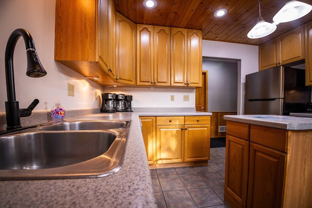 kitchen featuring dark tile patterned flooring, hanging light fixtures, sink, stainless steel refrigerator, and wooden ceiling