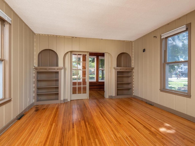 unfurnished living room with light wood-type flooring and a textured ceiling