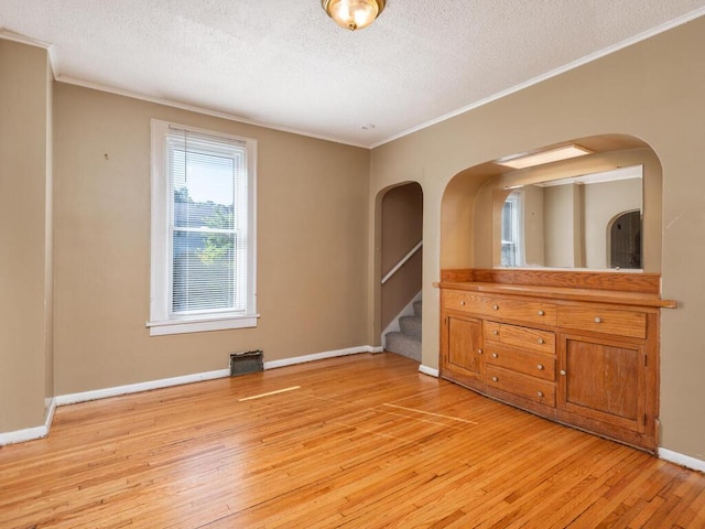 unfurnished room with light hardwood / wood-style floors, crown molding, and a textured ceiling