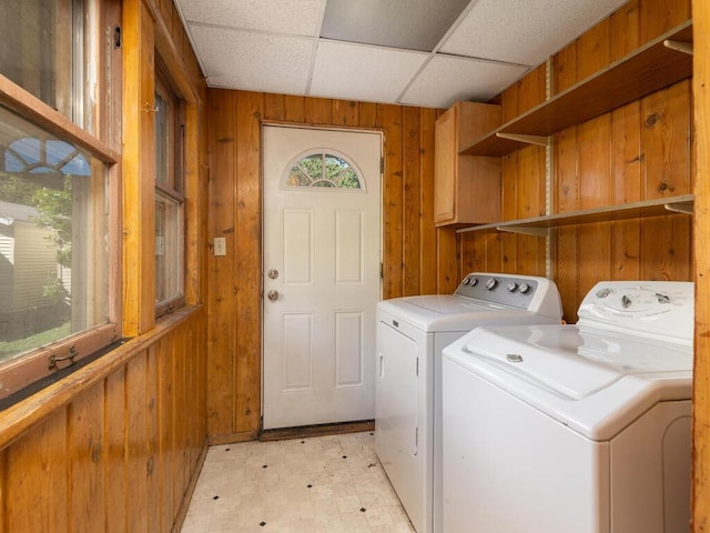 laundry area with wooden walls and washer and clothes dryer