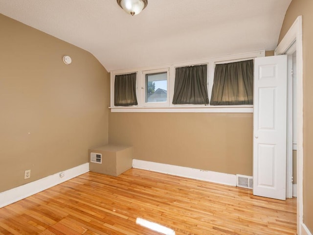 spare room featuring light wood-type flooring and lofted ceiling