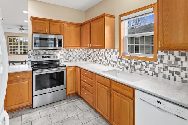 kitchen featuring appliances with stainless steel finishes, tasteful backsplash, ceiling fan, sink, and light tile patterned floors