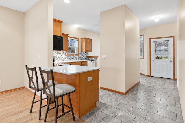 kitchen featuring a kitchen breakfast bar, stove, tasteful backsplash, white dishwasher, and a center island