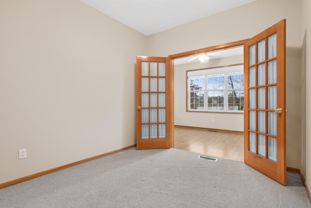 carpeted spare room with french doors and a textured ceiling