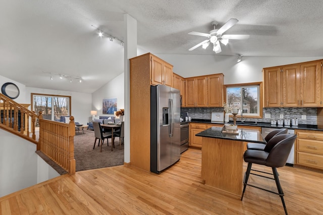 kitchen featuring stainless steel appliances, lofted ceiling, and dark countertops