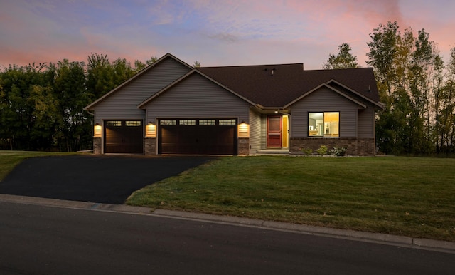 view of front of house featuring aphalt driveway, a lawn, and an attached garage