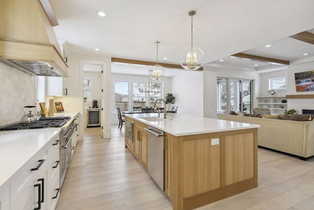 kitchen with pendant lighting, a chandelier, sink, light hardwood / wood-style flooring, and a center island with sink