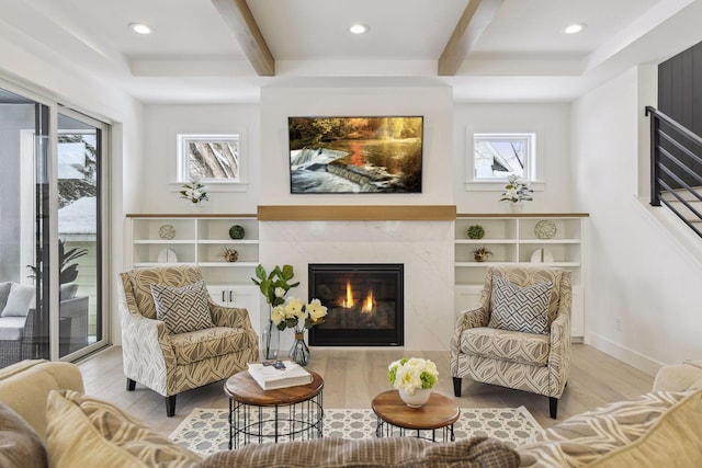 living area featuring light wood-type flooring, a premium fireplace, and beam ceiling