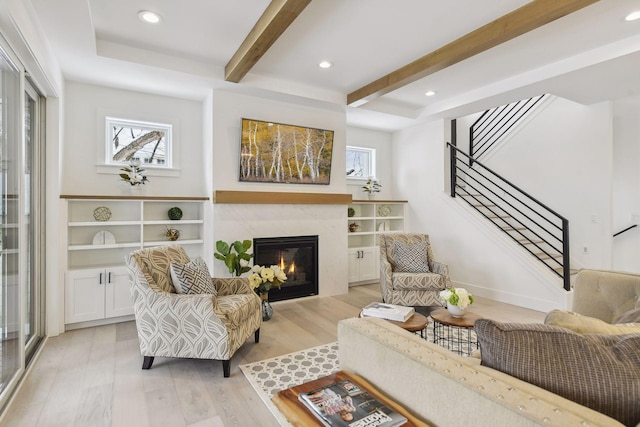 living room featuring light hardwood / wood-style floors, beamed ceiling, and a fireplace