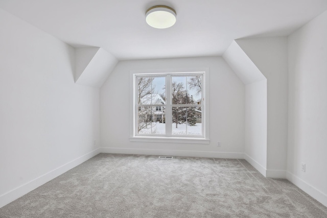 bonus room with vaulted ceiling and light colored carpet