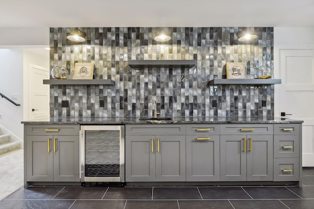 bar featuring dark stone counters, gray cabinetry, wine cooler, and tasteful backsplash