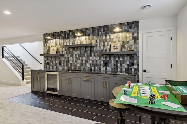 bar with gray cabinetry, decorative backsplash, beverage cooler, and dark colored carpet