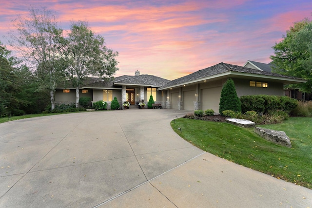 view of front of home with stucco siding, a front yard, an attached garage, a chimney, and driveway