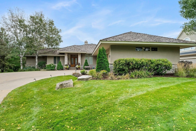 view of front of property with a front lawn, curved driveway, and stucco siding