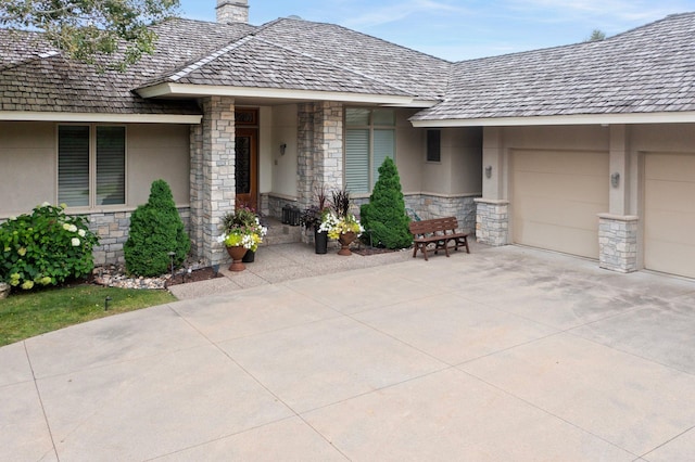 entrance to property with a garage, driveway, stone siding, and stucco siding