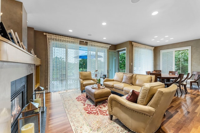 living area with recessed lighting, a tile fireplace, and wood finished floors