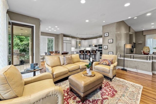 living room featuring track lighting, light wood finished floors, baseboards, and recessed lighting