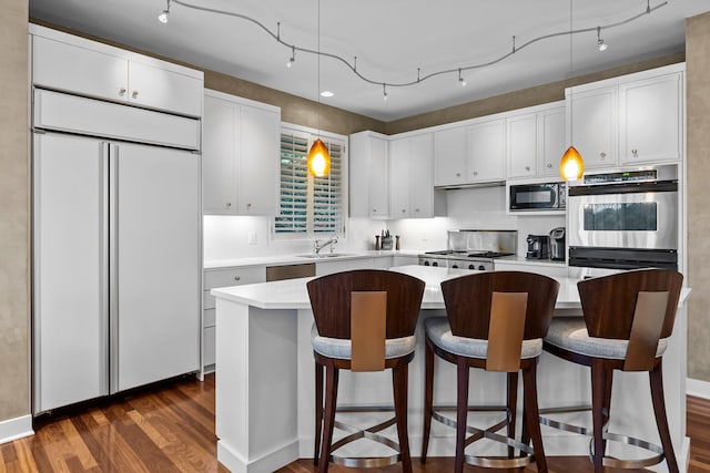 kitchen featuring built in appliances, a sink, light countertops, dark wood finished floors, and a kitchen island