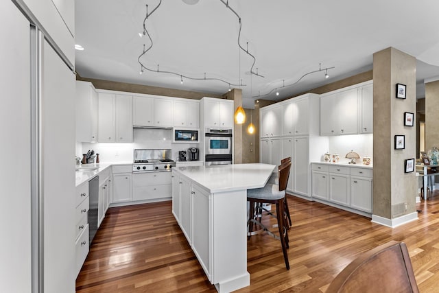 kitchen with a center island, light wood finished floors, white cabinets, and a kitchen breakfast bar