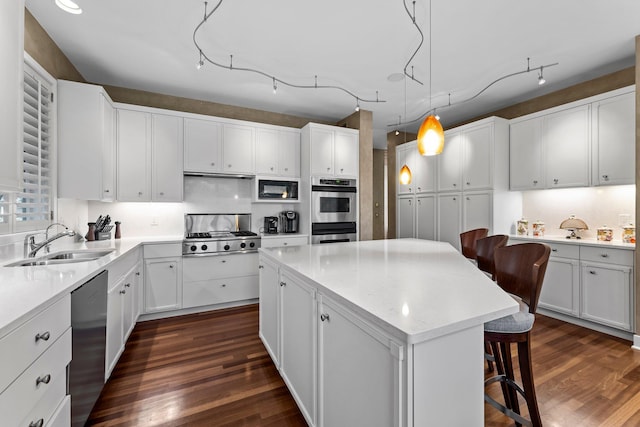 kitchen featuring a kitchen breakfast bar, a kitchen island, dark wood-type flooring, stainless steel appliances, and a sink