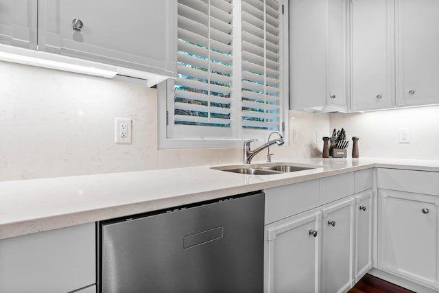 kitchen with stainless steel dishwasher, a sink, and white cabinets