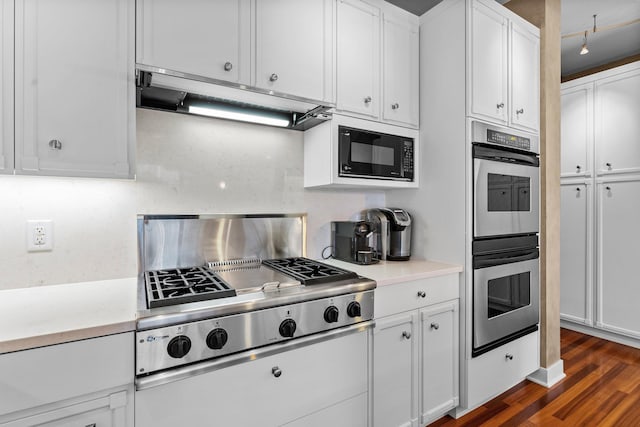 kitchen with under cabinet range hood, decorative backsplash, light countertops, and appliances with stainless steel finishes