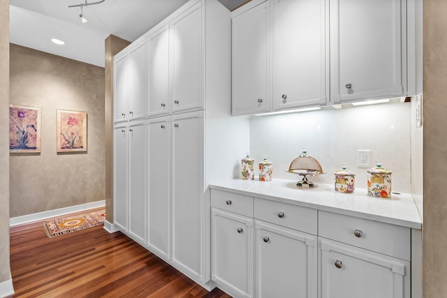 kitchen featuring dark wood-type flooring, white cabinetry, and baseboards