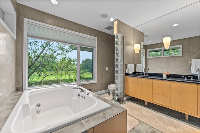 full bath with a sink, toilet, double vanity, and a jetted tub