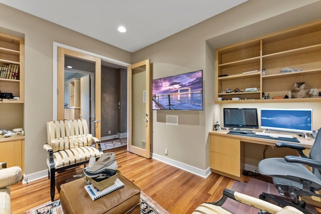 office space featuring built in shelves, light wood-type flooring, and baseboards