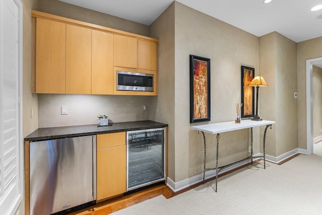 kitchen featuring wine cooler, stainless steel microwave, fridge, and baseboards