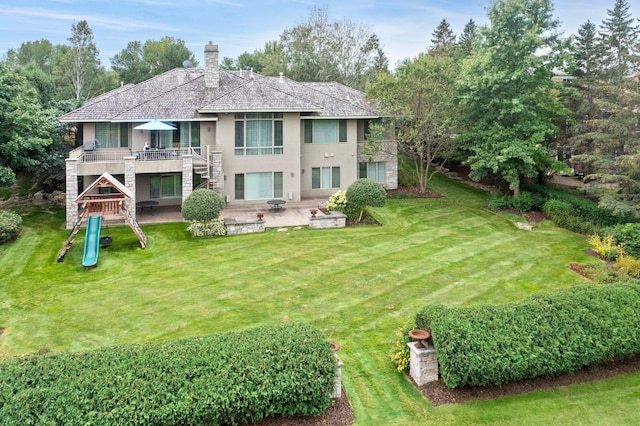 rear view of property with stucco siding, a chimney, a patio area, playground community, and a lawn