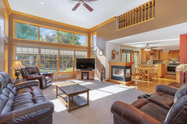 living room featuring a towering ceiling, a healthy amount of sunlight, and ornamental molding